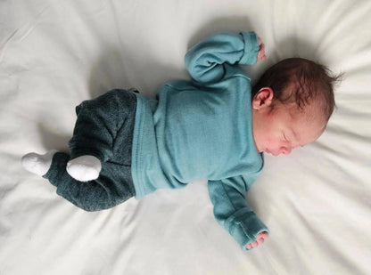 Newborn baby wearing a blue outfit lying on a white surface