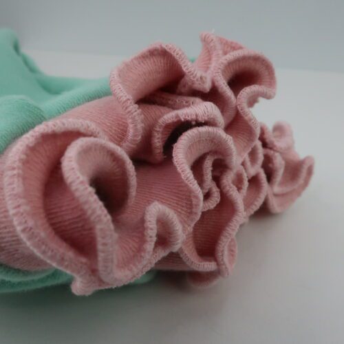 Bottom Additions- Double Ruffle cuffs. Double Ruffle cuffs are made by cuffing the cuff in half and finishing both cut edges with a ruffle rolled finish. This pair is a light green body with a light pink cuff with matching thread.