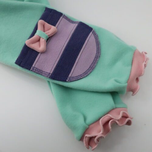 Bottoms Additions- Bows. A small bow made out of merino wool, attached directly onto an item or onto a pocket on the item.