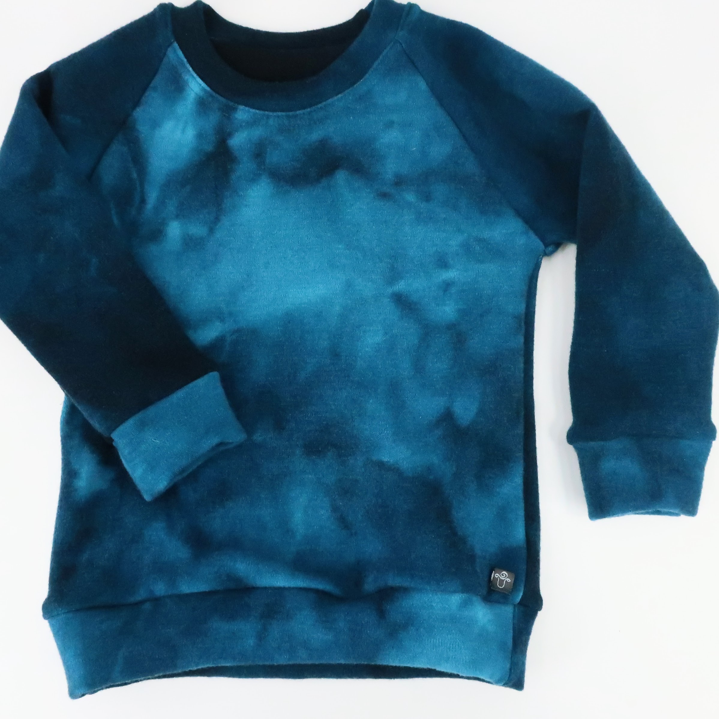 Merino Wool Simple Crew Neck Sweater. With cuffed raglan sleeves and a classic rounded crew neck. This sweater is a tie dyed blues colour.