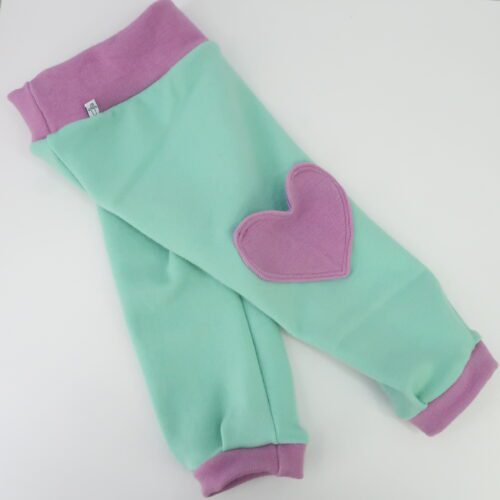 Bottom Additions- Heart Cargo Pocket. A cargo pocked in the shape of a heart that is lined in our lightweight merino wool. The heart has a double stitch around the outside. This pair has a pink heart, matching the pink cuffs and waistband on a light green pants.